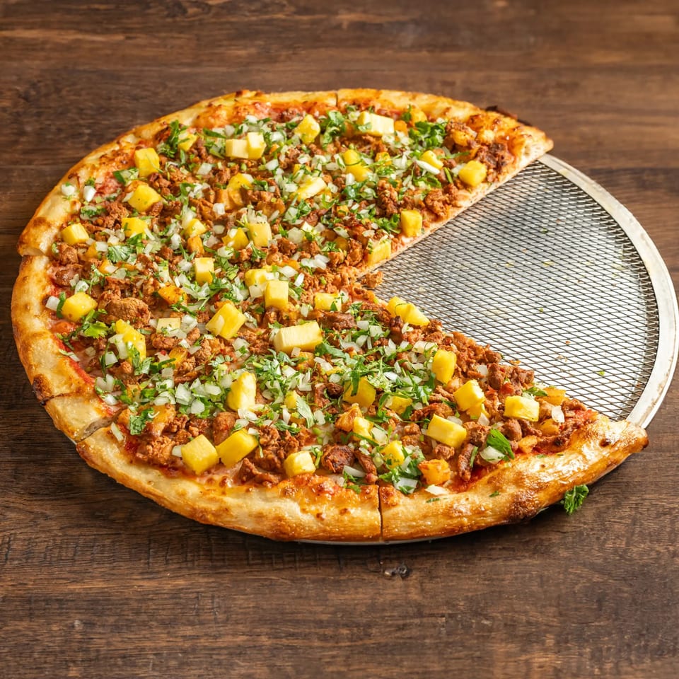 Taqueria El Mercadito's Mexican pizza with pineapple, ground meat, onions, and cilantro, with one slice removed.