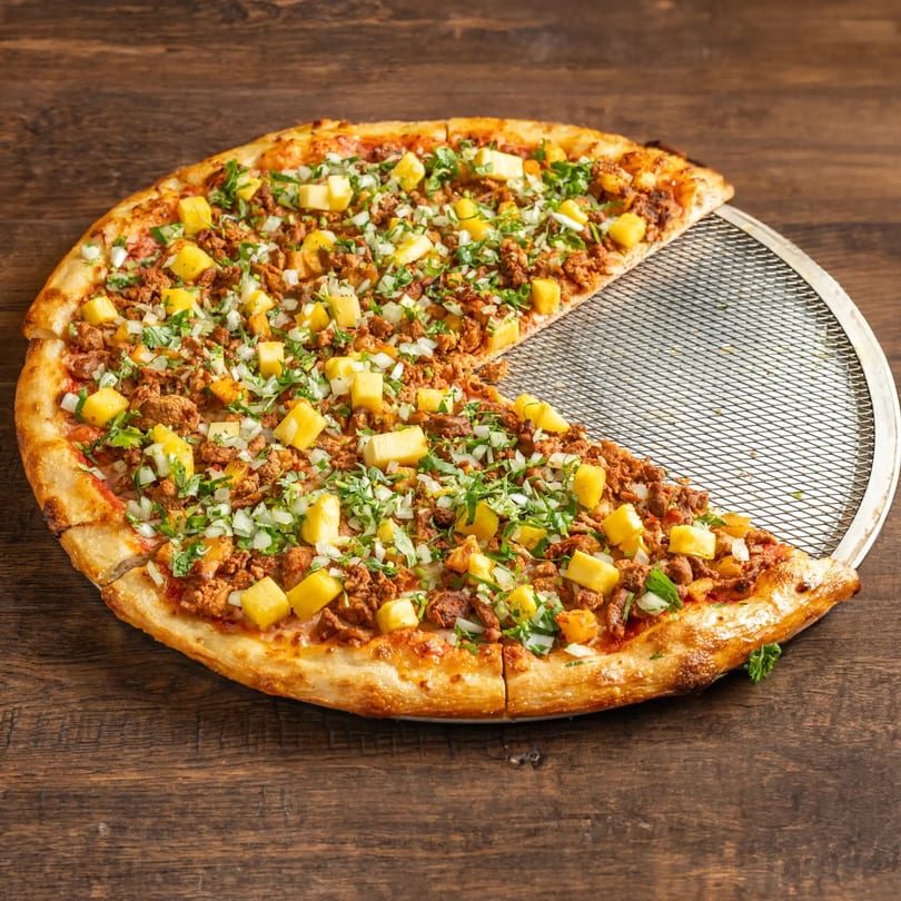 Taqueria El Mercadito's Mexican pizza with pineapple, ground meat, onions, and cilantro, with one slice removed.
